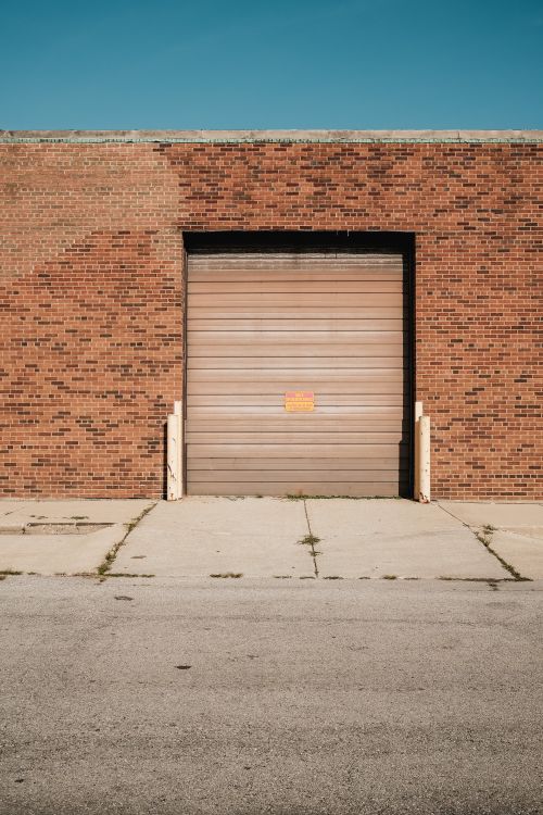 Brick industrial building featuring a closed metal garage door.